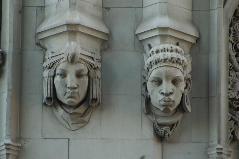 Two carved stone faces, one African, the other Asian.