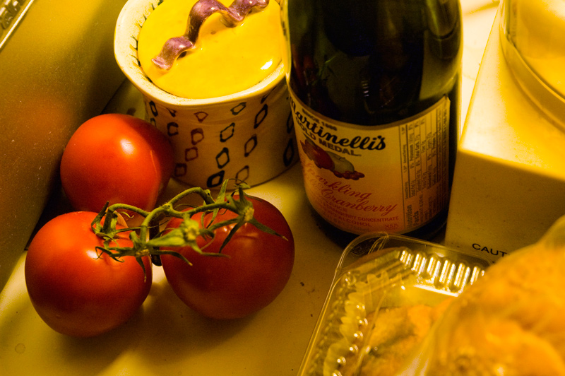 Sparkling cider and tomatoes on a kitchen counter top.