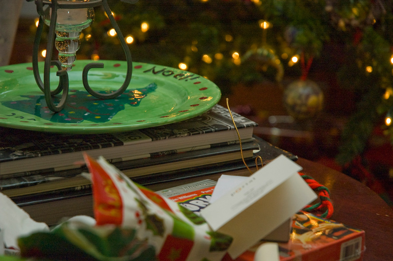 A green holiday plate, wrapping paper, and Christmas tree.