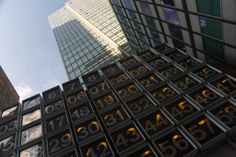 An array of lit numbers, below a skyscraper.