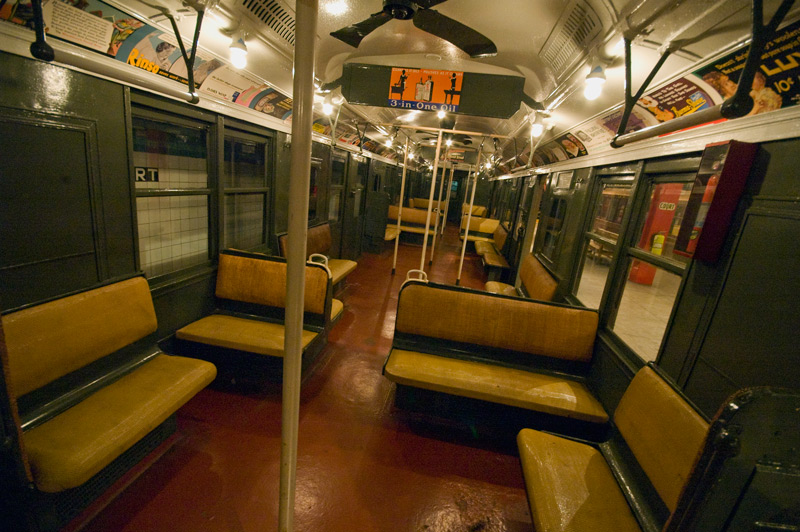 The interior of an old subway car, with cushioned benches.