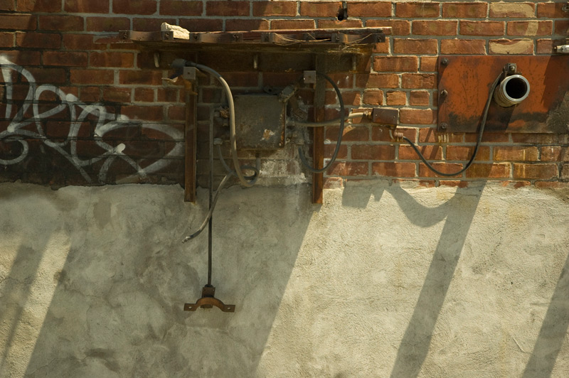 Pipes and other protrusions cast shadows on a brick wall
