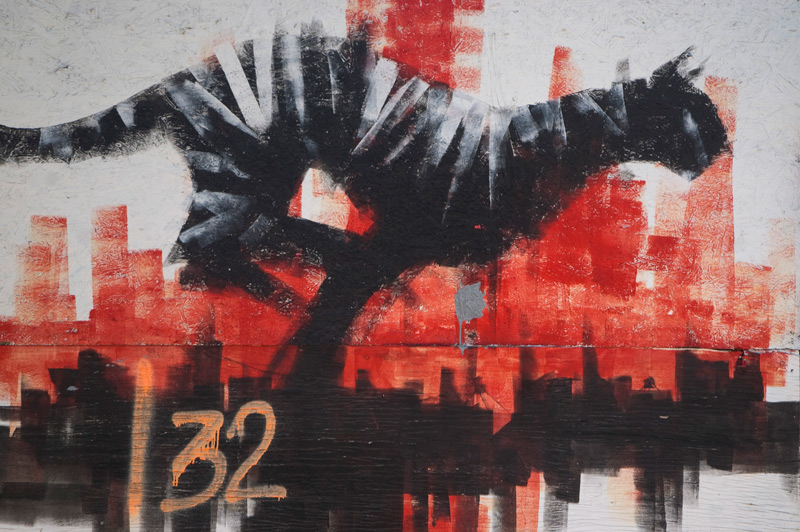 A mural shows a big cat running against a red cityscape.