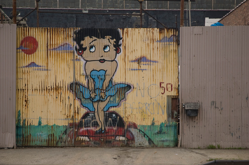 An auto shop has a mural of Betty Boop on top of a sports car.