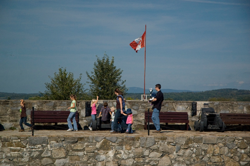 A family of tourists stroll on top of a fort's stone wall.