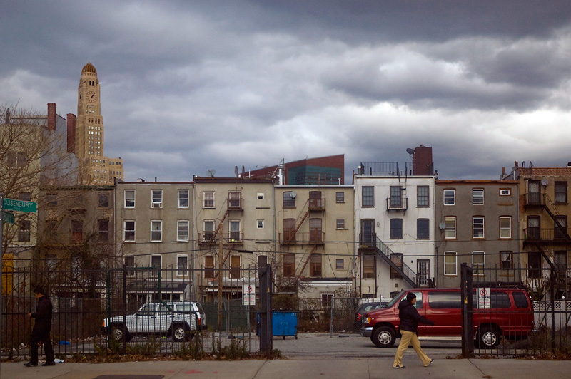 A cloudy sky above the rear sides of tenements.