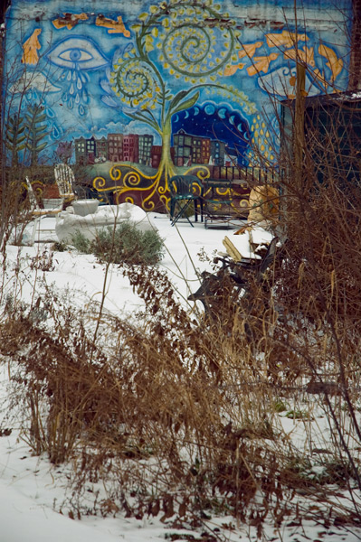 A blue mural overlooks a snow-covered garden.