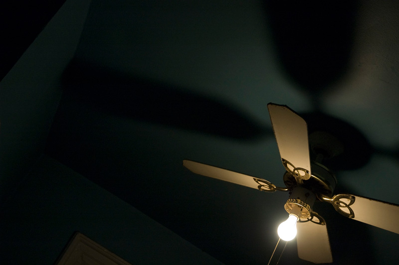 A ceiling fan with a bare light bulb.
