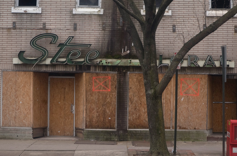 A burnt-out storefront, showing smoke damage and destroyed neon signs.