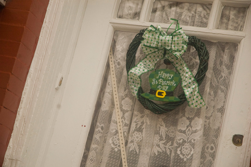 A green wreath on a door with St. Patrick's Day wishes.