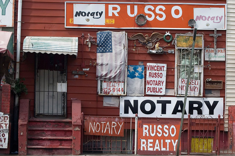 Homemade signs on a red wooden building advertising notary public and real estate services
