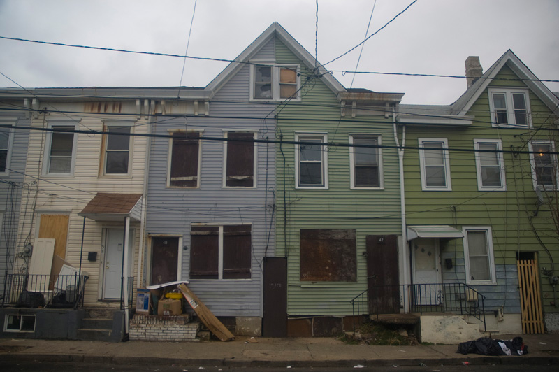 Two boarded-up homes, with refuse out front