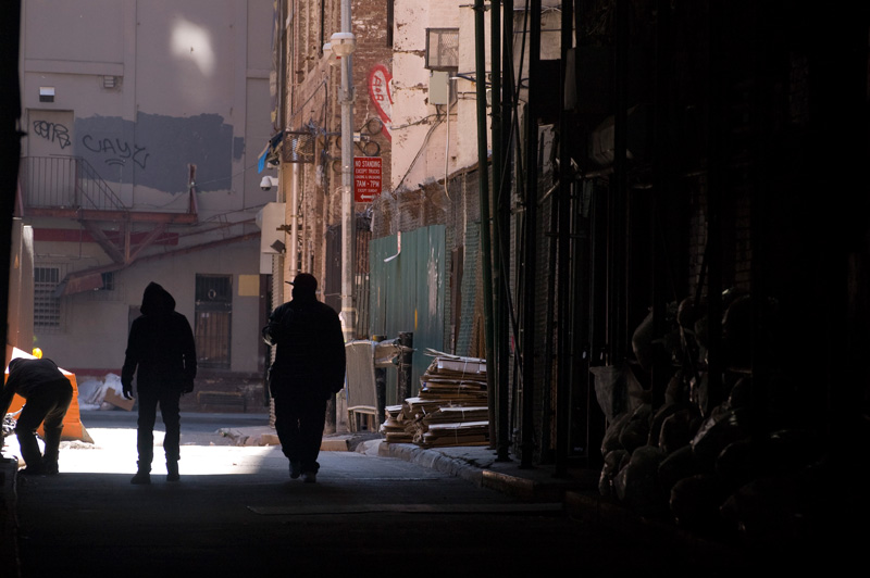 Three people in an alley, in silhouette