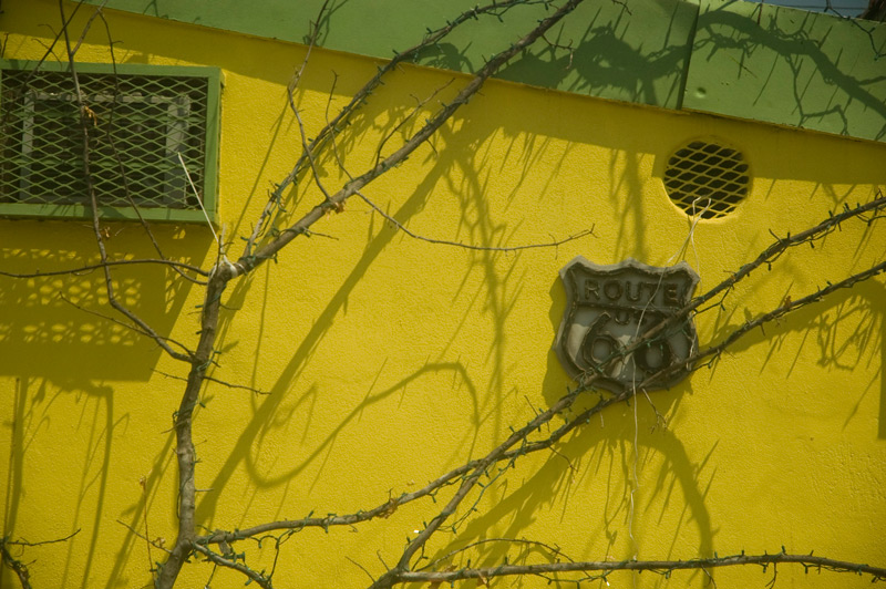 An old sign for Route 66 hangs on a yellow wall
