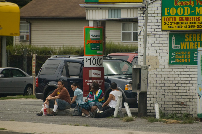 Four people sitting by gasoline pumps.