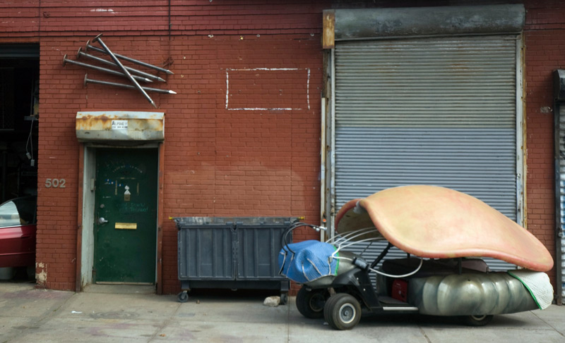 A beetle-shaped electric cart, near a door with large nails.