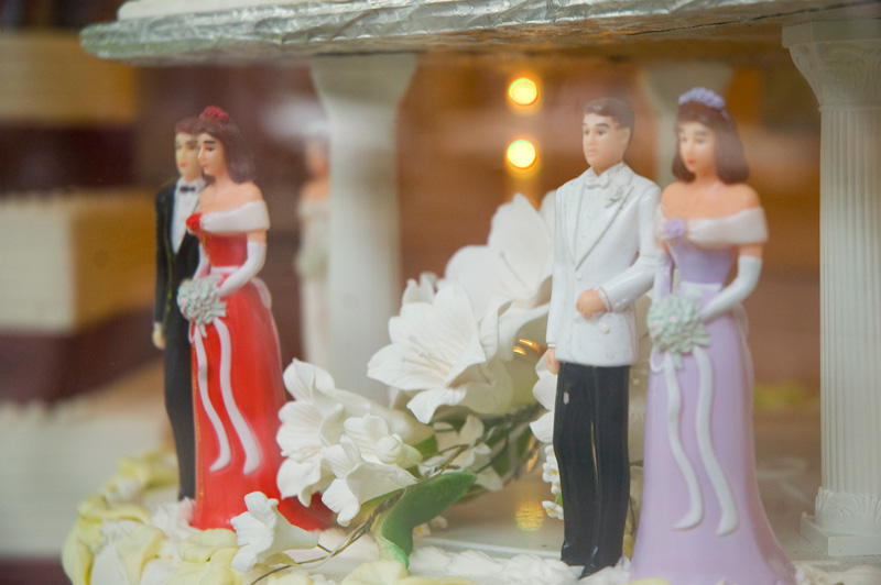 Two pairs of plastic bridal couples on display wedding cakes.