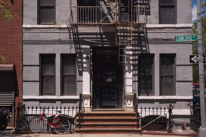 Entrance to a row house, with fire escapes above.