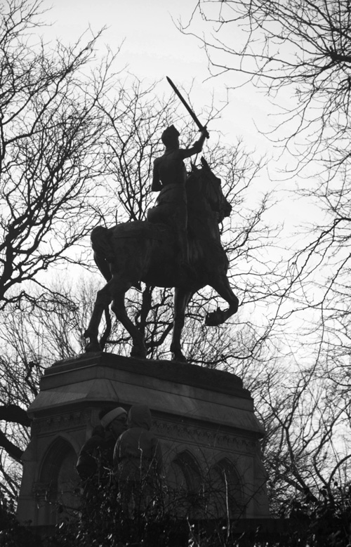 A silhouette of a statue of Joan of Arc in armor and on a horse, with sword raised.