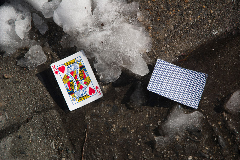 A discarded King of Hearts, lying near snow.