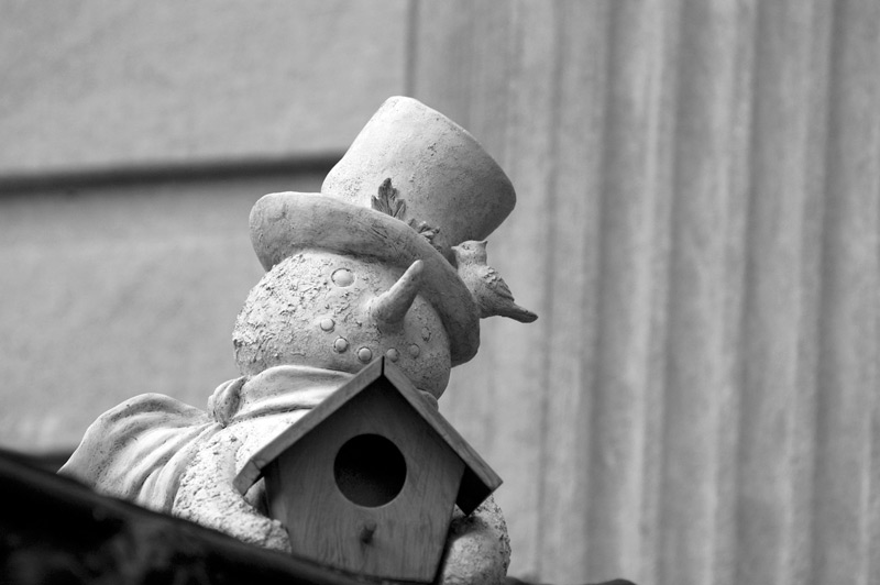 A decorative snowman holding a bird house.