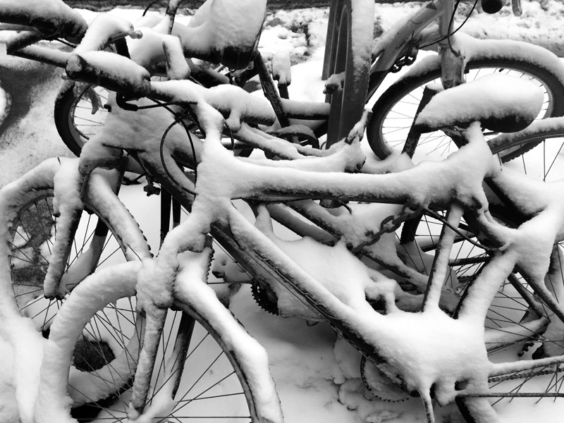 A jumble of bicycles, covered in snow.