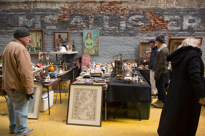 A man stares at another person at a flea market.