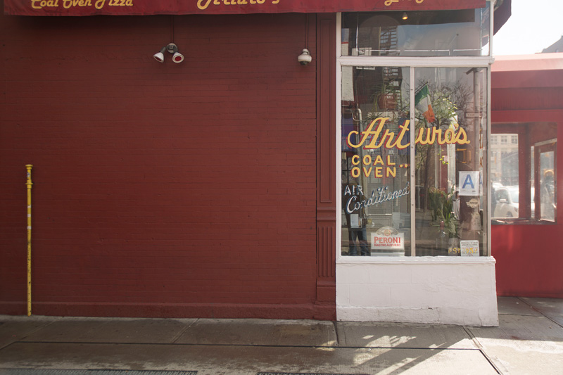 A pizza parlor's window, with hand-lettered signage.