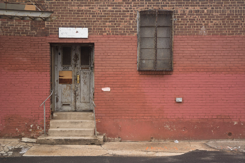 A wooden grey door in a brick building.