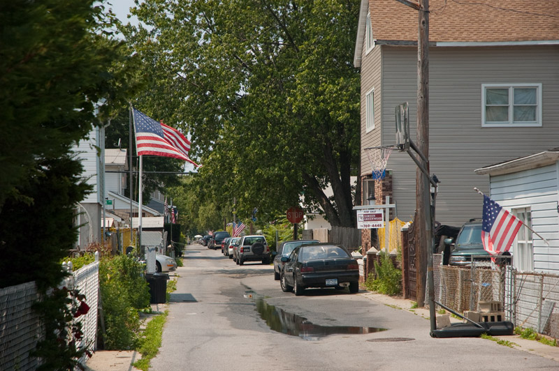 A small residential street, lined with American flags.