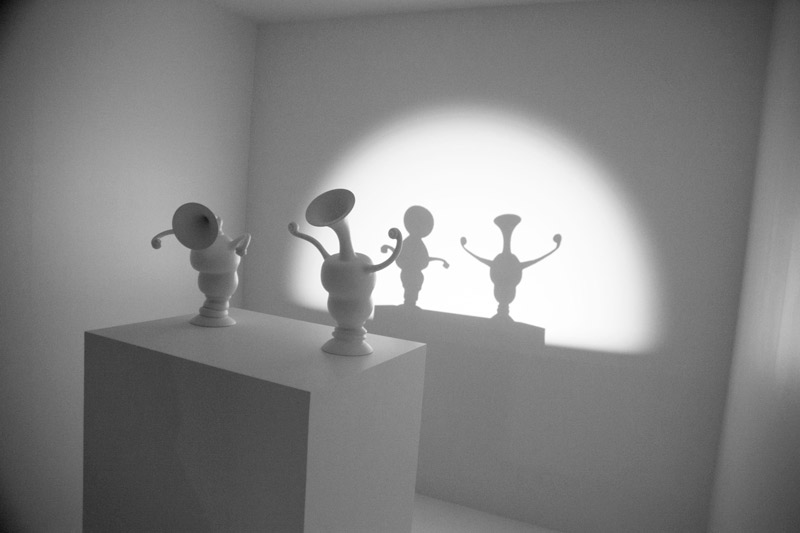 Shadows on a wall, behind cartoonish vases.