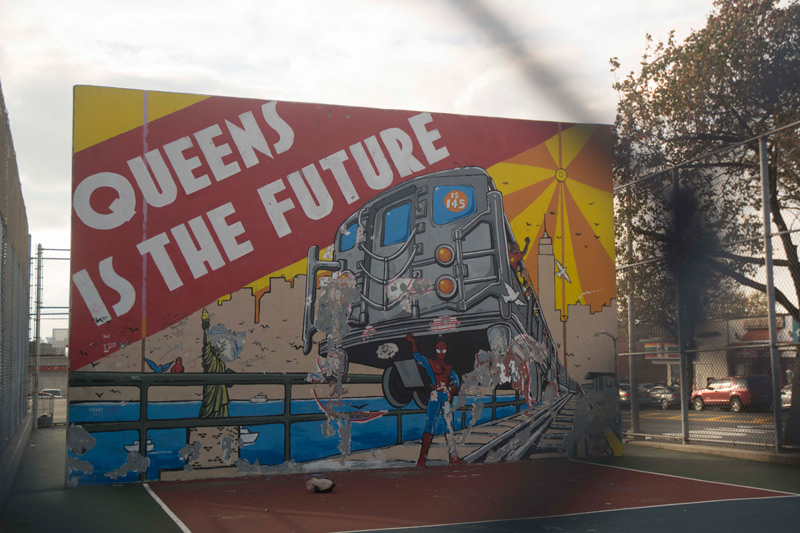 A mural shows Spider-Man hoisting a subway train, and the headline 'Queens is the Future'.