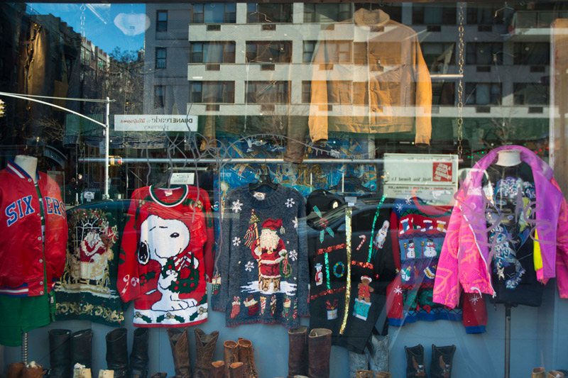 Ugly Christmas sweaters on display in a store window.