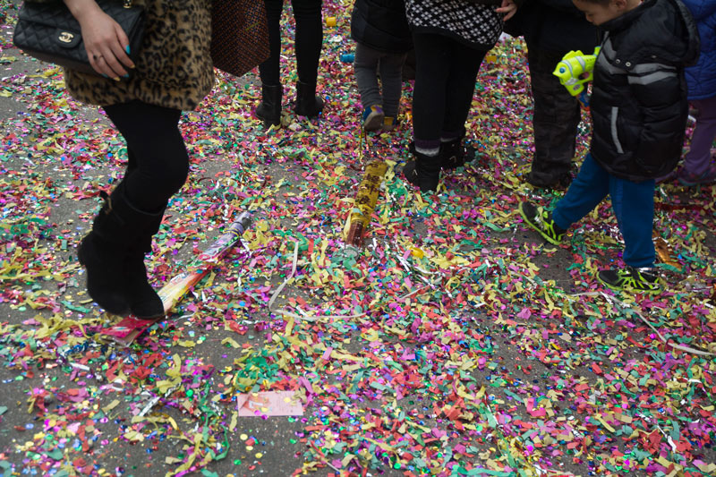 People on a sidewalk covered in confetti.