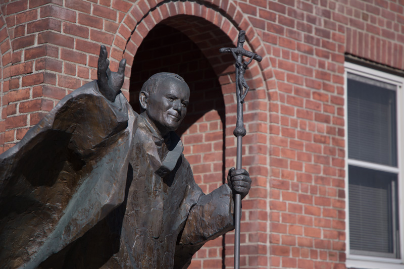A statue of Pope John Paul II, with a staff that has a crucifix at its head.