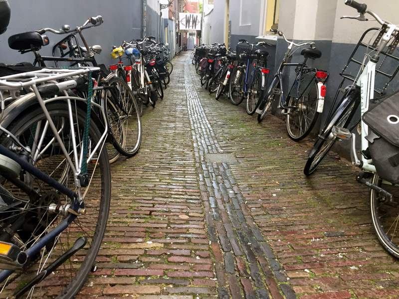 A cobblestone alley, with bikes on both sides.