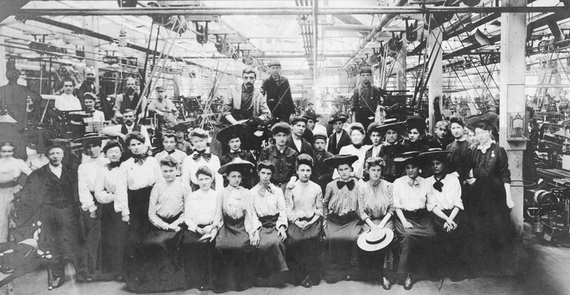 Early 20th Century factory workers, mostly women, dressed in their best for a group photograph.
