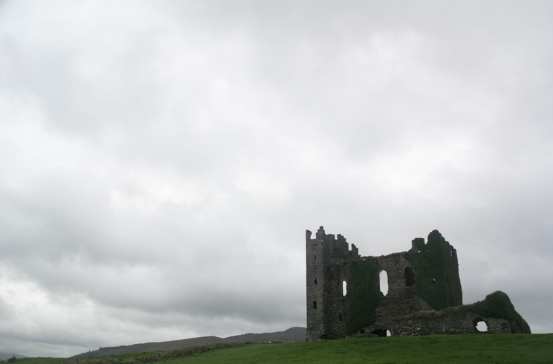 The ruins of an abandoned castle, against a grey sky.
