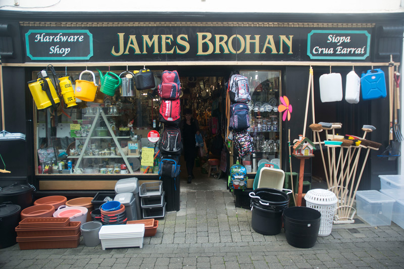 An Irish hardware store with goods out front; its signage has 'Hardware Shop' in both English and Irish.