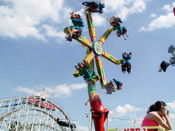 Kids spinning in the air on a spider-like ride,
with the cyclone roller coaster in the background.