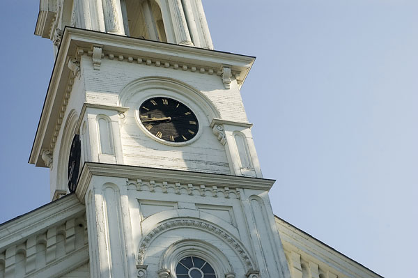 A clock face decorates the side of a white steeple.