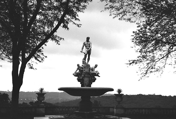 A statue stands over other figures and a water fountain.